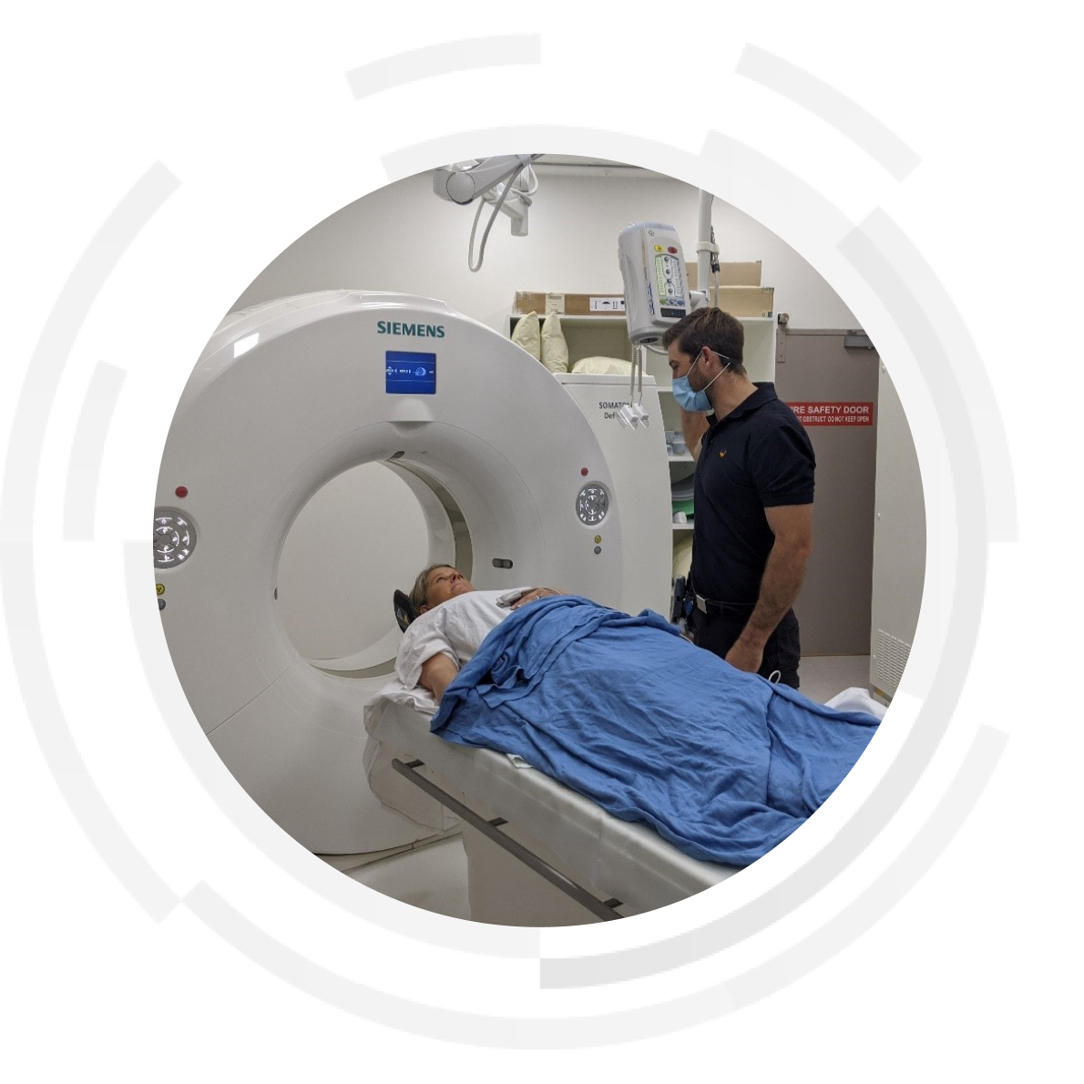 Patient lying in MRI bed with nurse standing on the side.