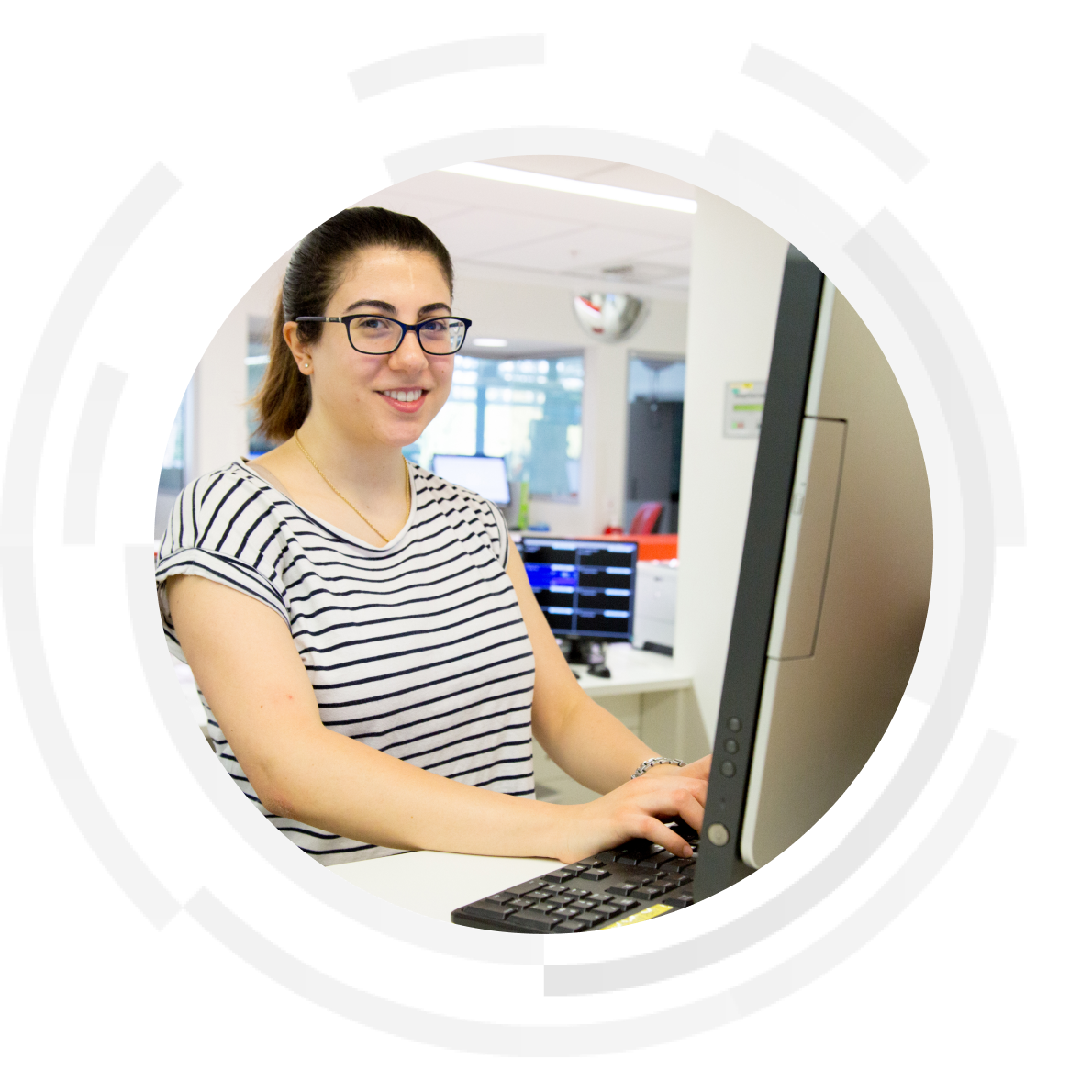 Smiling female doctor working at a desktop computer entering data.