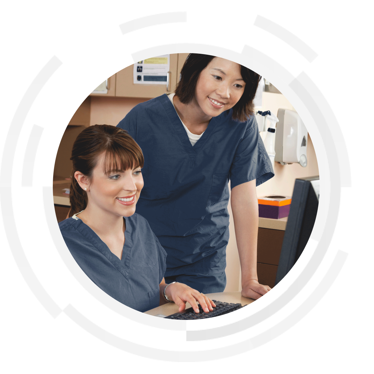 Two smiling female clinicians entering data into a desktop computer.
