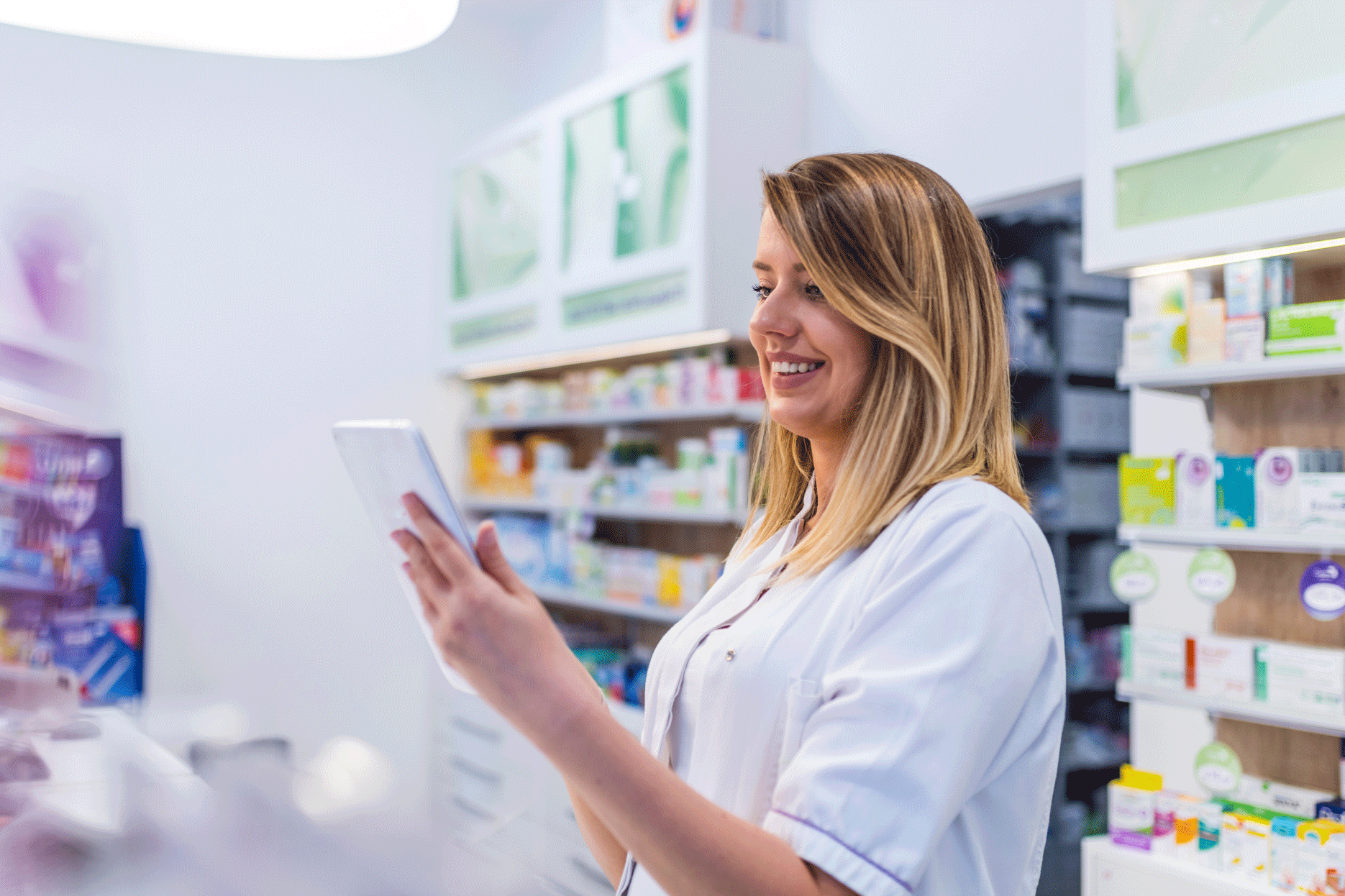 Pharmacist looking at tablet and smiling