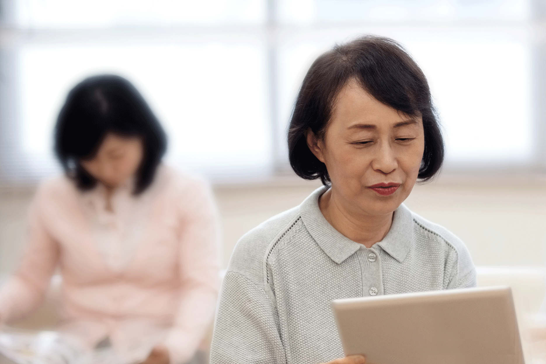 Asian woman looking at tablet device.