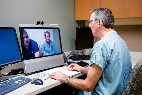 Clinician doing a virtual consultation via video with two patients