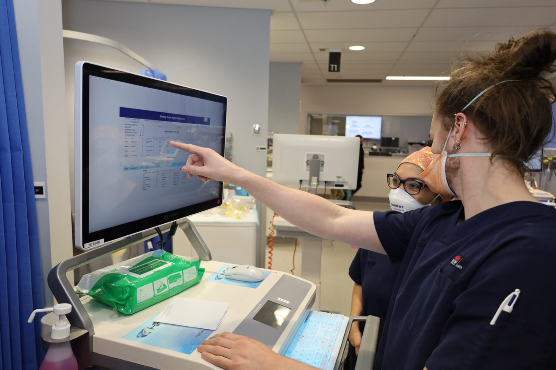 Two hospital clinicians pointing to a computer monitor.