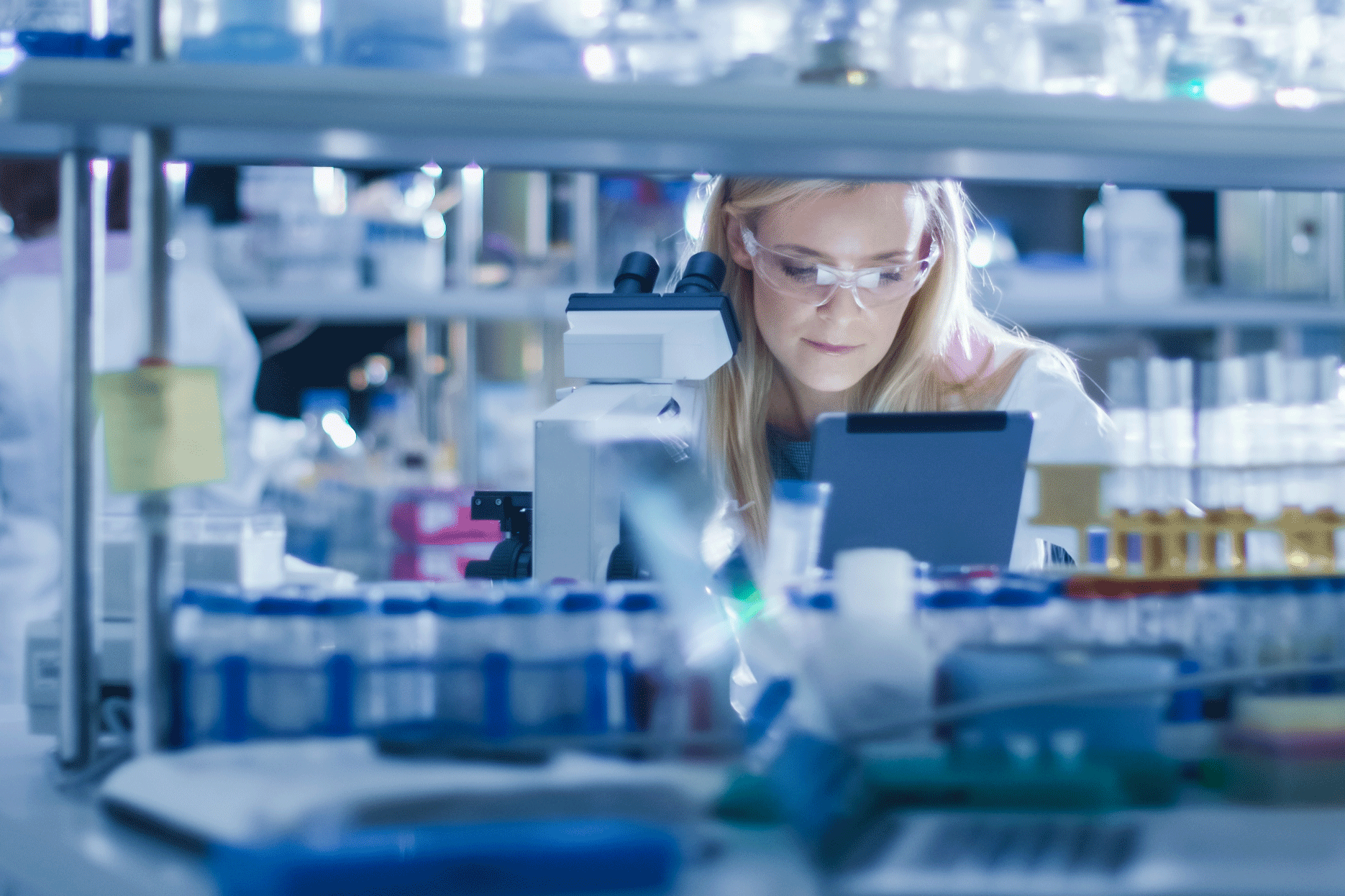 Woman in lab coat and glasses working in a laboratory.