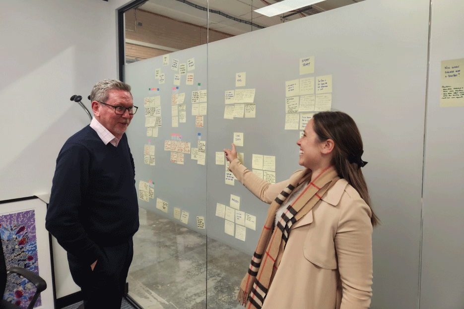 Male and female coworker brainstorming with post-it notes on a wall