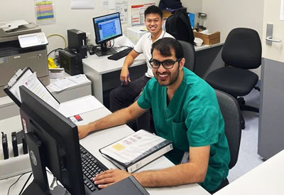Doctor and pharmacist smiling at desks