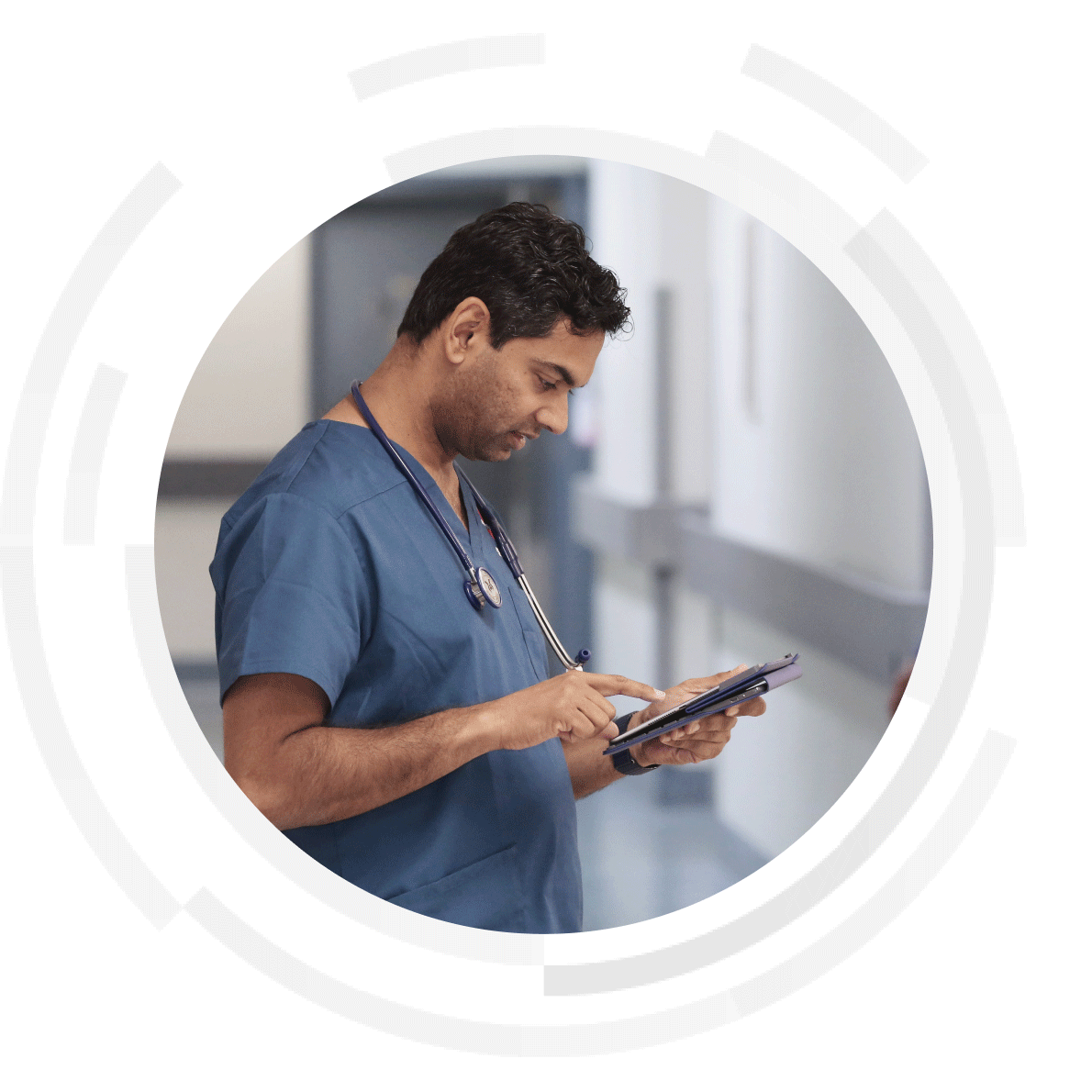 Male clinician using a tablet in a hospital hallway.