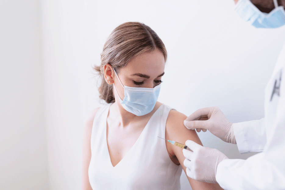 Woman wearing a mask receiving a vaccination in your left arm