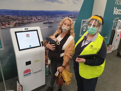 Customer and NSW Health employee standing in front of NSW Health Vaccination Administration Management Platform system