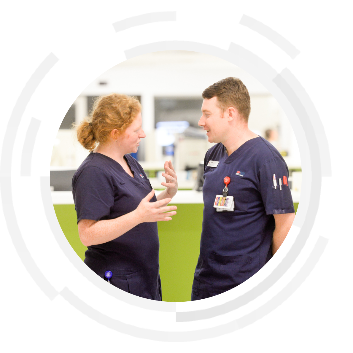 Female and male nurse having a discussion at the nurses station.