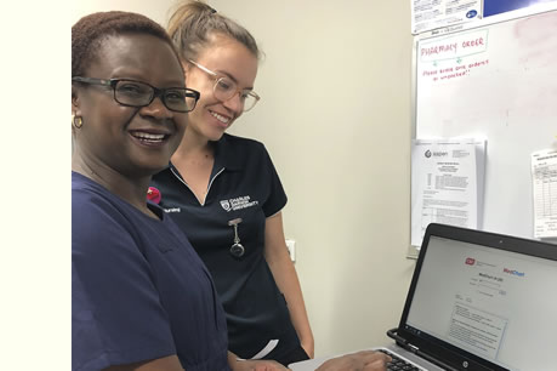 Two smiling female clinicians working at a computer.